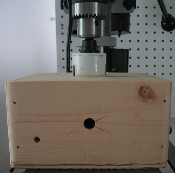 Scoring the bottom base board's reinforcement piece with a drill press by passing through the hole in the top base board.