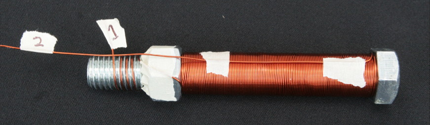 Three layers of wire have been wrapped around the core. Before continuing with the fourth layer, the wire was brought back up the length of the bolt's shaft in order to create a center tap.